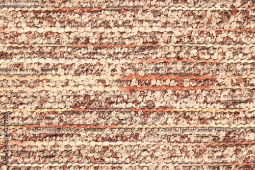 Beige-orange fabric sample with textured bouclé weave. Textiles and wool. Blank background and close-up.