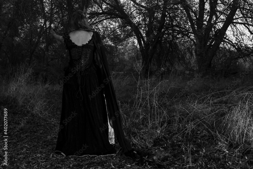 Woman in dark classical clothes, in the middle of the forest Woman in dark classical clothes, in the middle of the forest