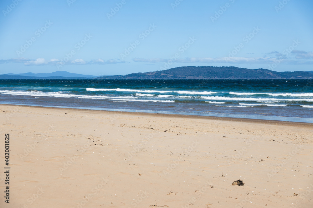 pristine wild landscape at Clifton Beach in Tasmania, Australia with wavy blue ocean and golden sand next to a rugged coastline pristine wild landscape at Clifton Beach in Tasmania, Australia with wavy blue ocean and golden sand next to a rugged coastline