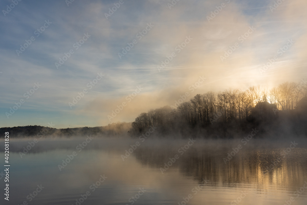 Fototapeta premium The sun rises over the foggy waters of Lake Lanier during winter in Georgia; silence; peace