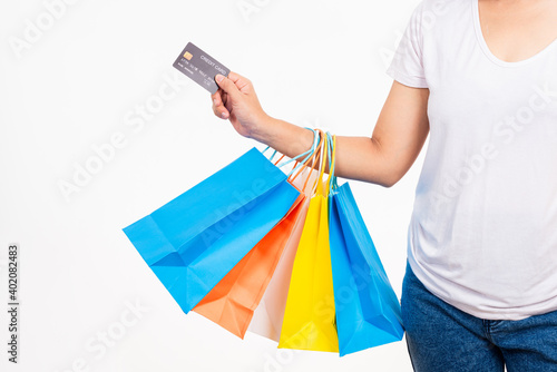 Happy woman hand holding shopping bags multicolor and credit card for shopping online, young female hold many packets within arms isolated on white background, Black Friday sale concept