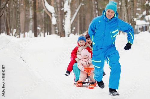 Dad sledges family in winter in the snow