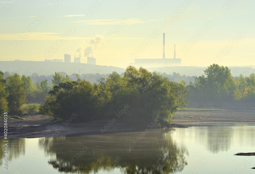 The Bank of the Ob river in the morning fog. CHPP-5 pipes in the distance on the horizon