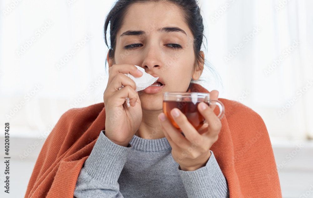 Woman with a cup of hot drink health problems runny nose headache orange plaid Woman with a cup of hot drink health problems runny nose headache orange plaid