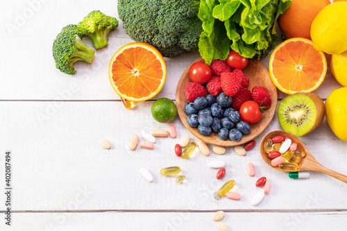 Fototapeta Naklejka Na Ścianę i Meble -  A top view of fresh fruits and vegetables with different medicine on a wooden spoon
