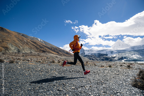 Woman trail runner cross country running in high altitude winter nature