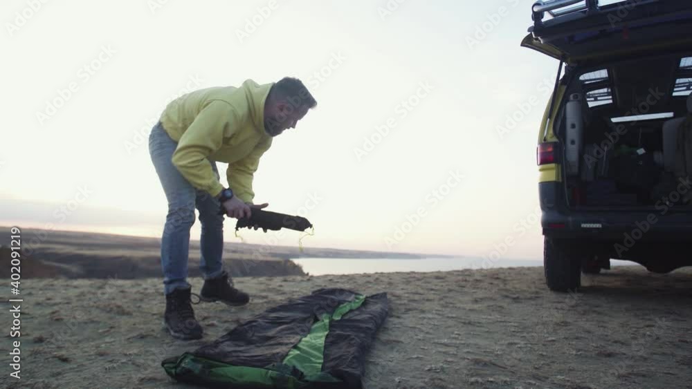 Young man in a yellow hoodie Setting up camping tent Young man in a yellow hoodie Setting up camping tent