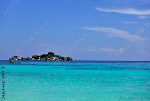 The clear aquamarine water of the Andaman Sea is calm. A small island with picturesque boulders is visible on the horizon. Cirrus clouds in the azure sky. Thailand. Similan islands © Вера 