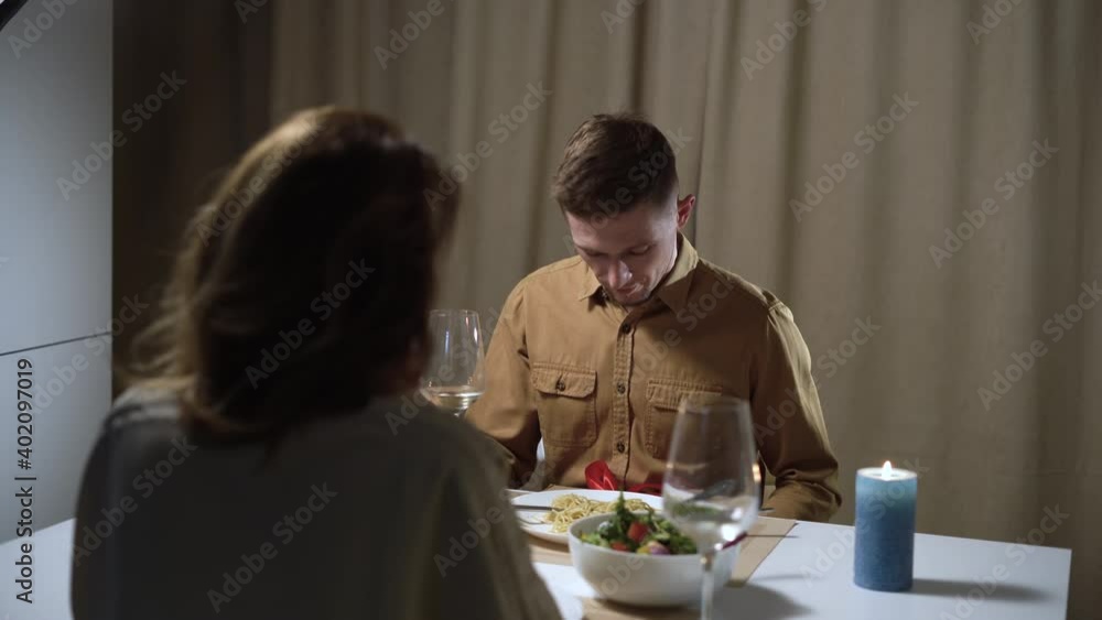 A man gives a gift. Happy couple in love having dinner at home, smiling and having fun during a romantic dinner. A man gives a gift. Happy couple in love having dinner at home, smiling and having fun during a romantic dinner.
