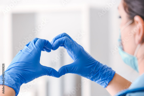 Female doctor showing heart shape with hands, closeup