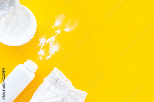 Set of children's cosmetics on a yellow background, top view, copy space, mockup. Baby hygiene, trendy minimalistic background. Flat lay composition diaper, powder, cream