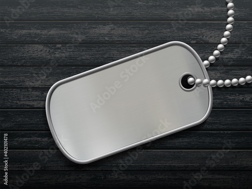 Military metal id tag on a black wooden background