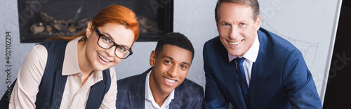 Smiling multicultural businesspeople looking at camera in meeting room, banner.