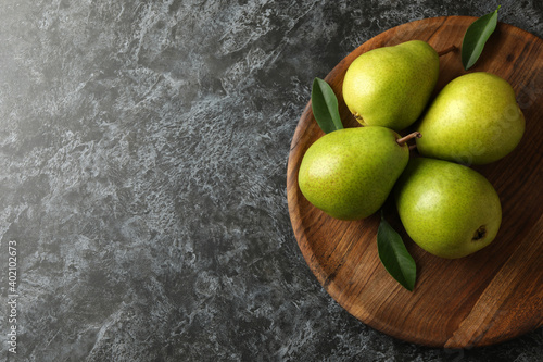 Wooden tray with green pears on black smokey background