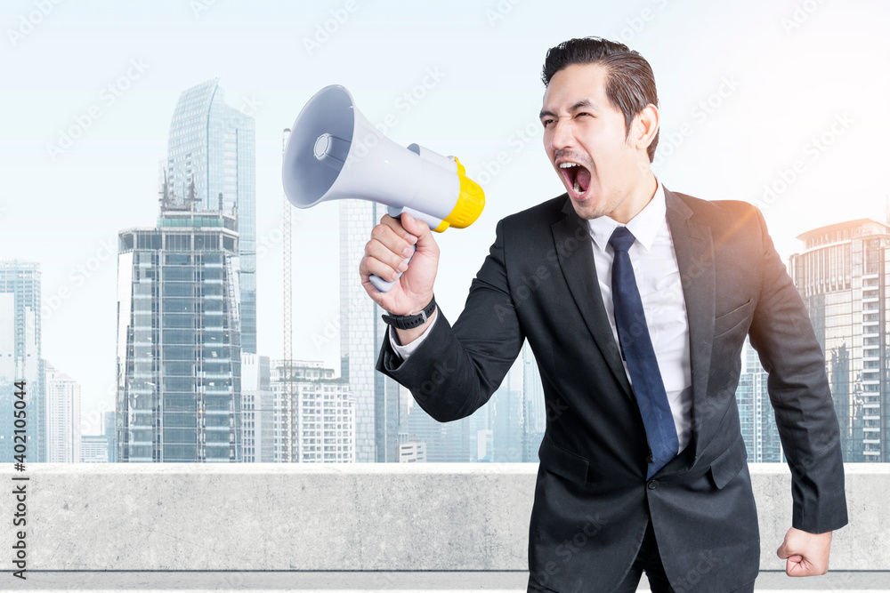 Asian businessman shouting something on megaphone Asian businessman shouting something on megaphone