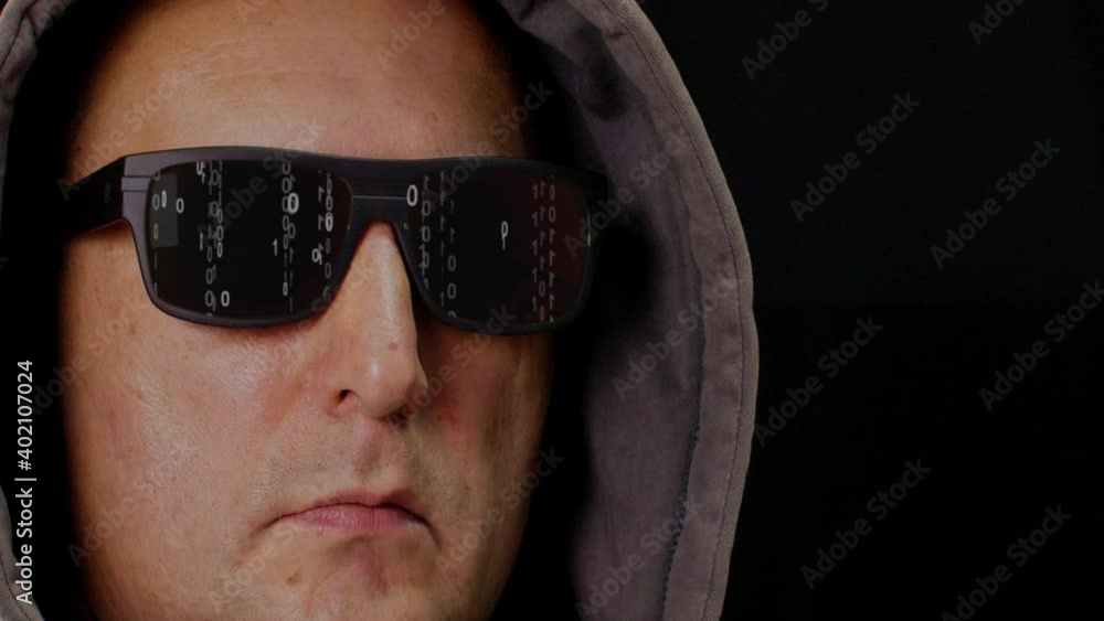 Man in hood and eyeglasses with digital rain matrix. Close-up view of serious middle aged man in hoodie and sunglasses with binary code numbers on black background Man in hood and eyeglasses with digital rain matrix. Close-up view of serious middle aged man in hoodie and sunglasses with binary code numbers on black background