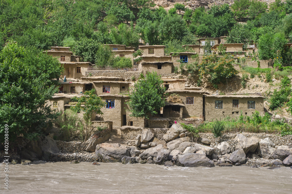 Fototapeta premium View of remote rural Afghan village along the Panj river seen from Darvaz district in Gorno-Badakshan, the Pamir mountain region of Tajikistan