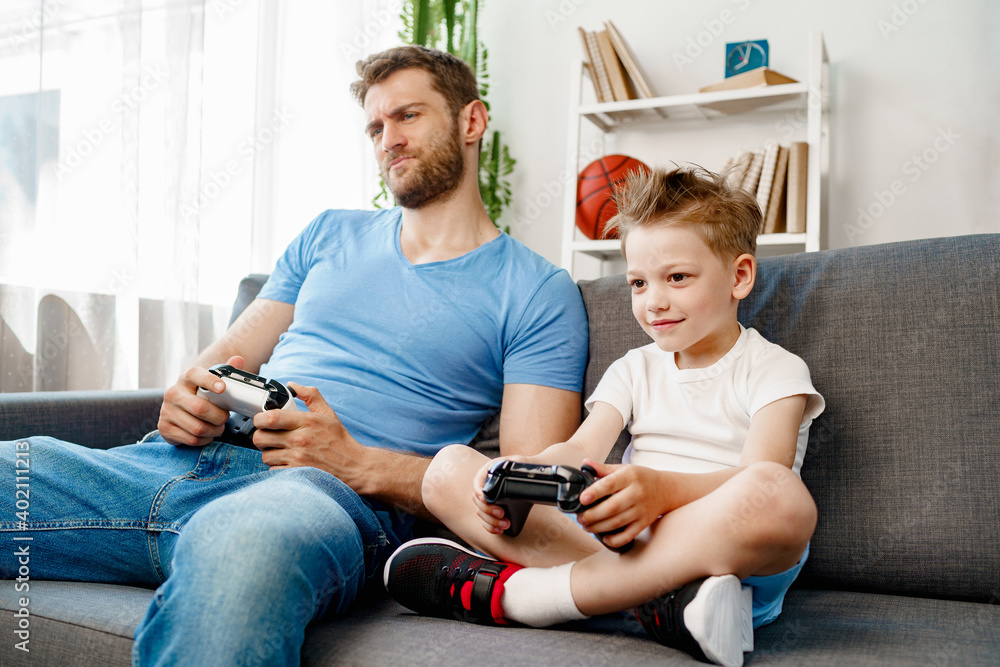 © fotofabrika - Father and his little son playing video games together at home