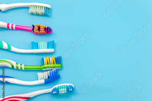 Multi-colored toothbrushes on a blue background. Flat composition with hand toothbrushes on colored background  close up with copy space.