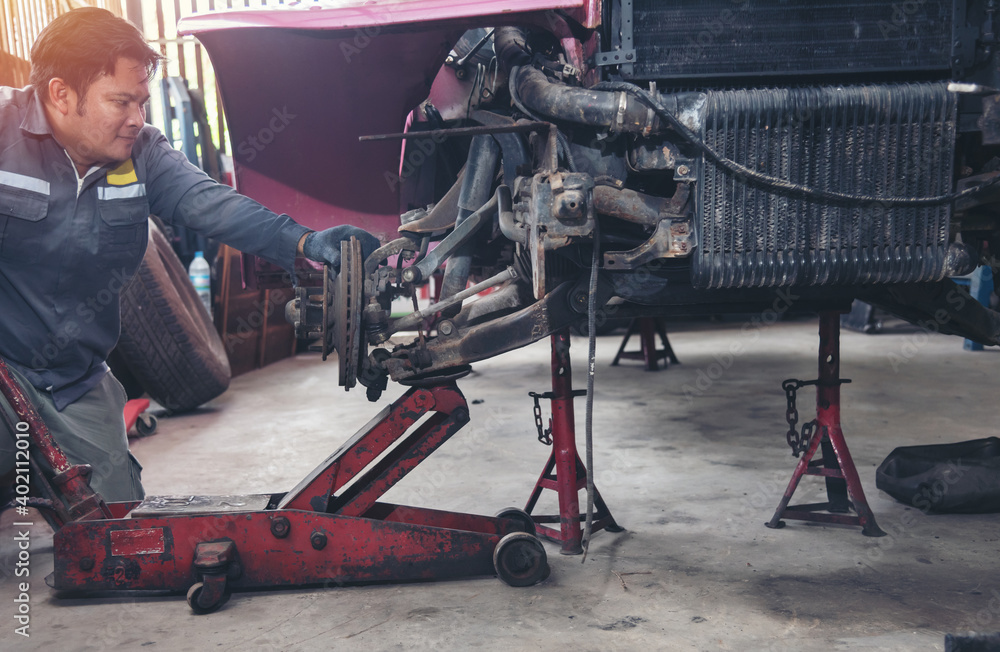 Fototapeta premium asia man in blue uniform car mechanic sitting check car engine motor machine at garage. owner sme business transport industrial people person concept