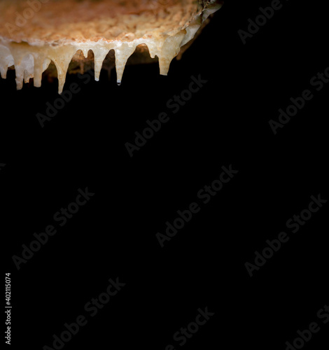 Stalactites with water drops over dark black background photo