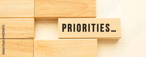 PRIORITIES text on a strip of wood lying on a white table.