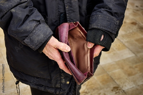 An elderly homeless poor woman holds an empty wallet, or purse. The concept of poverty in retirement. Global Extreme poverty. No money help me. Covid-19 Global Financial Crisis.