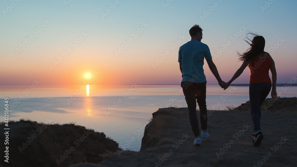 The man and woman walking holding hands on the beautiful seascape background