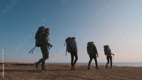 The four travelers with backpacks walking on the seascape background