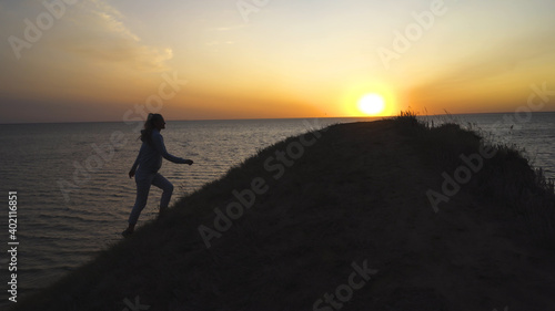 The woman climbing the hill on the seascape background