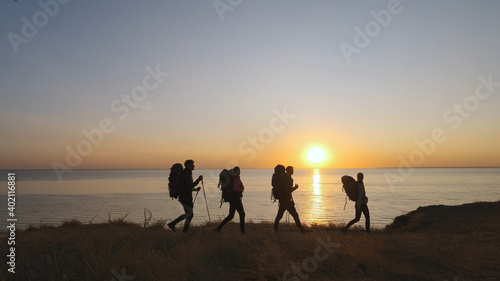 The four travelers with backpacks walking on the seascape background © realstock1