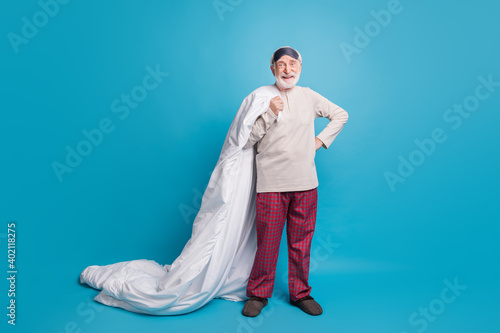 Full length photo portrait of excited old man in eye mask with blanket isolated on pastel blue colored background