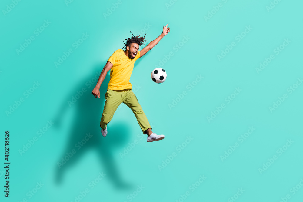 Full size photoo of young happy positive crazy african man jumping playing football isolated on turquoise color background