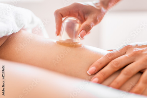 Masseur make massage with jars of cellulite on the buttock and thighs of patient. Treatment of excess weight, anti-cellulite, skin care