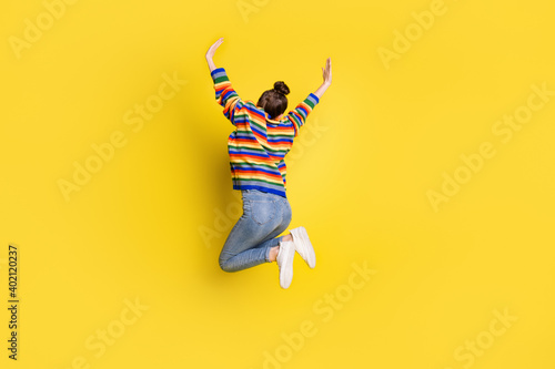 Full size back rear spine view photo of pretty girl jump up air raise hands wear rainbow color sweater isolated on vivid color background