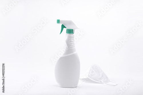 A closeup of alcohol spray bottle and facemask on a white background-concept COVID19 prevention photo