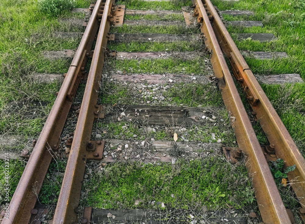 Old rusty metal rails and wooden sleepers on a dirt surface. Railroad for passenger and freight trains. Old rusty metal rails and wooden sleepers on a dirt surface. Railroad for passenger and freight trains.