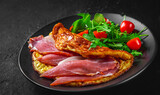 omelette with prosciutto and salad on black plate on Dark grey black slate background