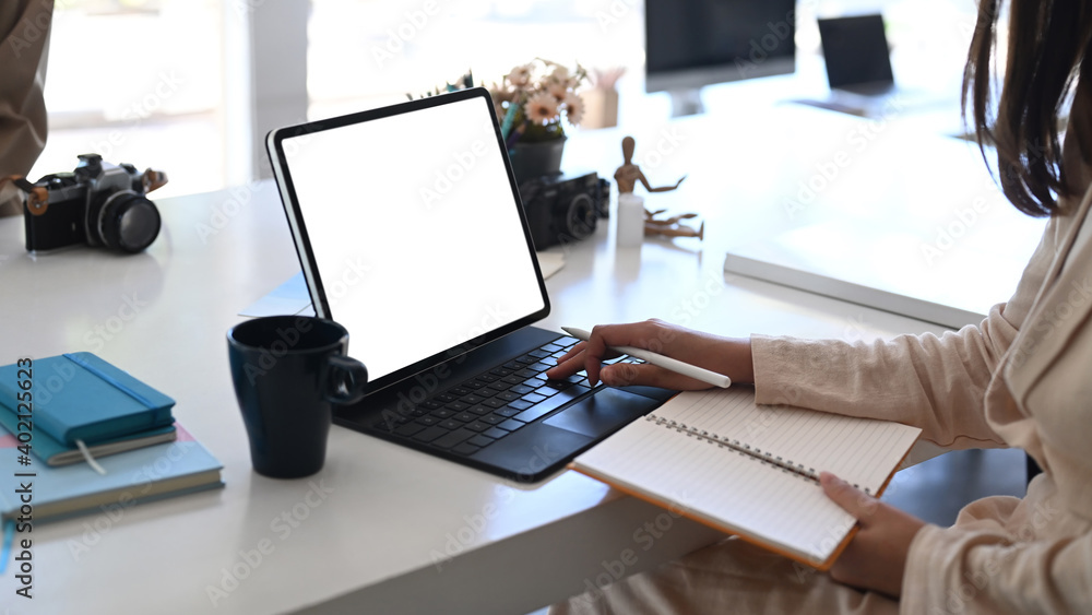Young businesswoman working on her project with tablet computer and holding notebook at office desk. Young businesswoman working on her project with tablet computer and holding notebook at office desk.