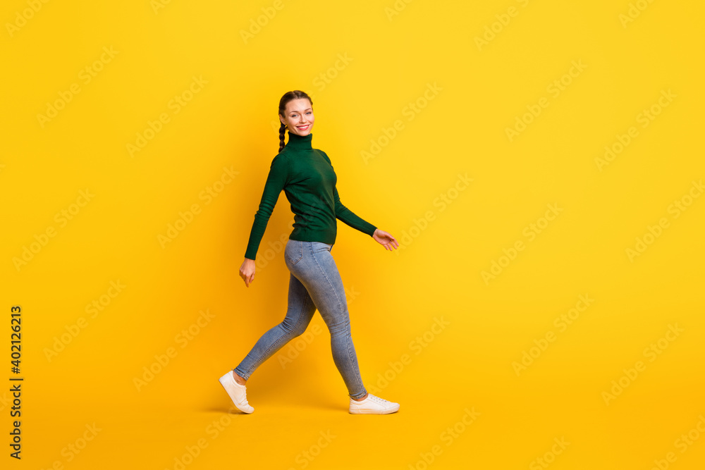 Full length body size photo female student with braids in turtleneck stepping forward smiling isolated on bright yellow color background