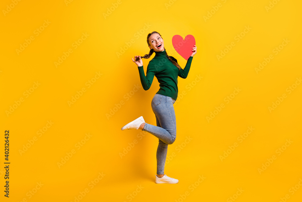 Full length body size photo funky girl looking blank space keeping red heart card on date isolated on vivid yellow color background