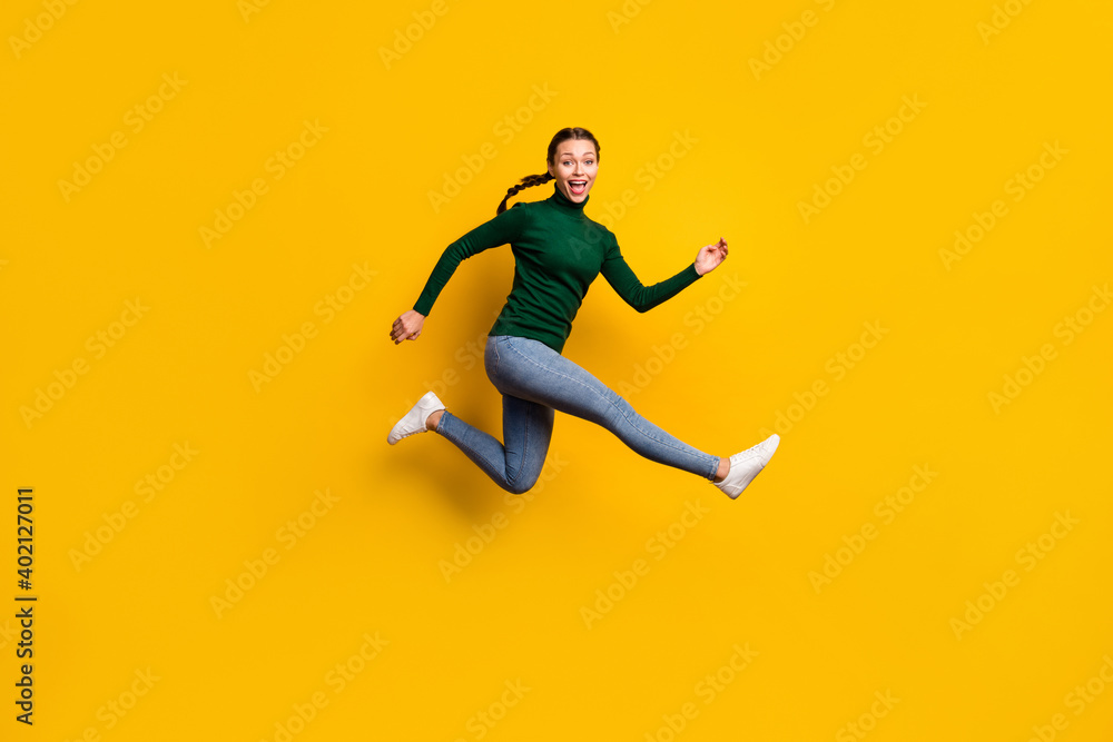 Full length body size photo smiling woman jumping high in stylish clothes isolated on vibrant yellow color background