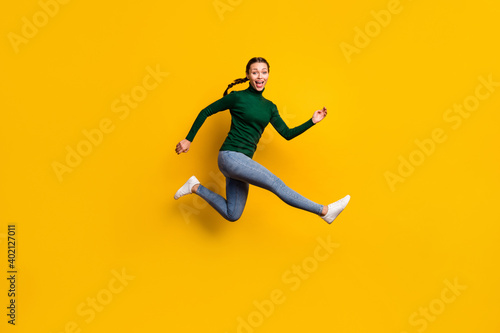 Full length body size photo smiling woman jumping high in stylish clothes isolated on vibrant yellow color background © deagreez