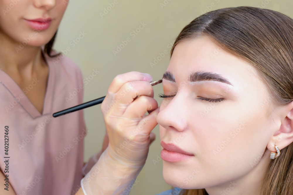 Eyebrow coloring. Woman applying brow tint with makeup brush closeup.