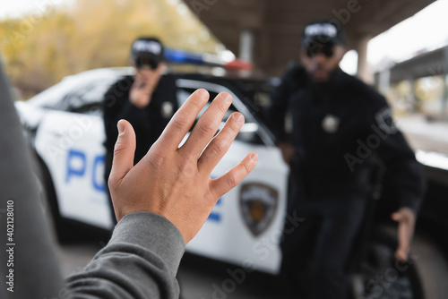 offender showing hand with blurred multicultural police officers on background outdoors.