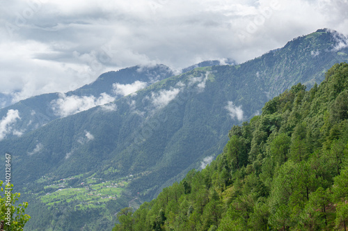 Landscape shot of tree covered mountains in the foreground with cloud covered mountain ranges in the distance and deep valleys showing the hill stations of India 