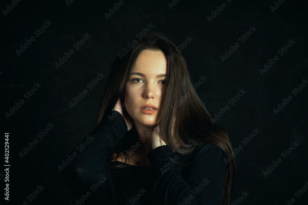 Fototapeta premium Portrait of a young beautiful woman in the studio on a dark background