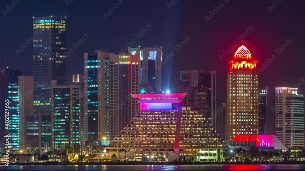 Doha skyscrapers in downtown skyline night timelapse, Qatar, Middle East Illuminated towers on a West Bay reflected in a water of Gulf. Doha skyscrapers in downtown skyline night timelapse, Qatar, Middle East Illuminated towers on a West Bay reflected in a water of Gulf.