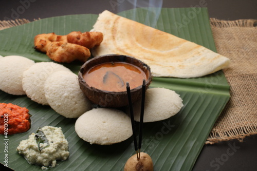 Fototapeta Naklejka Na Ścianę i Meble -  Group of South Indian food like Masala Dosa, Idli, Wada or vada, sambar, served over banana leaf with colourful coconut chutneys