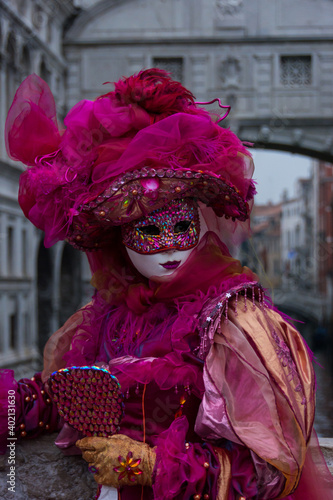 Venice, Italy - February 18, 2020: An unidentified woman in a carnival costume in front of Ponte dei Sospiri, attends at the Carnival of Venice.